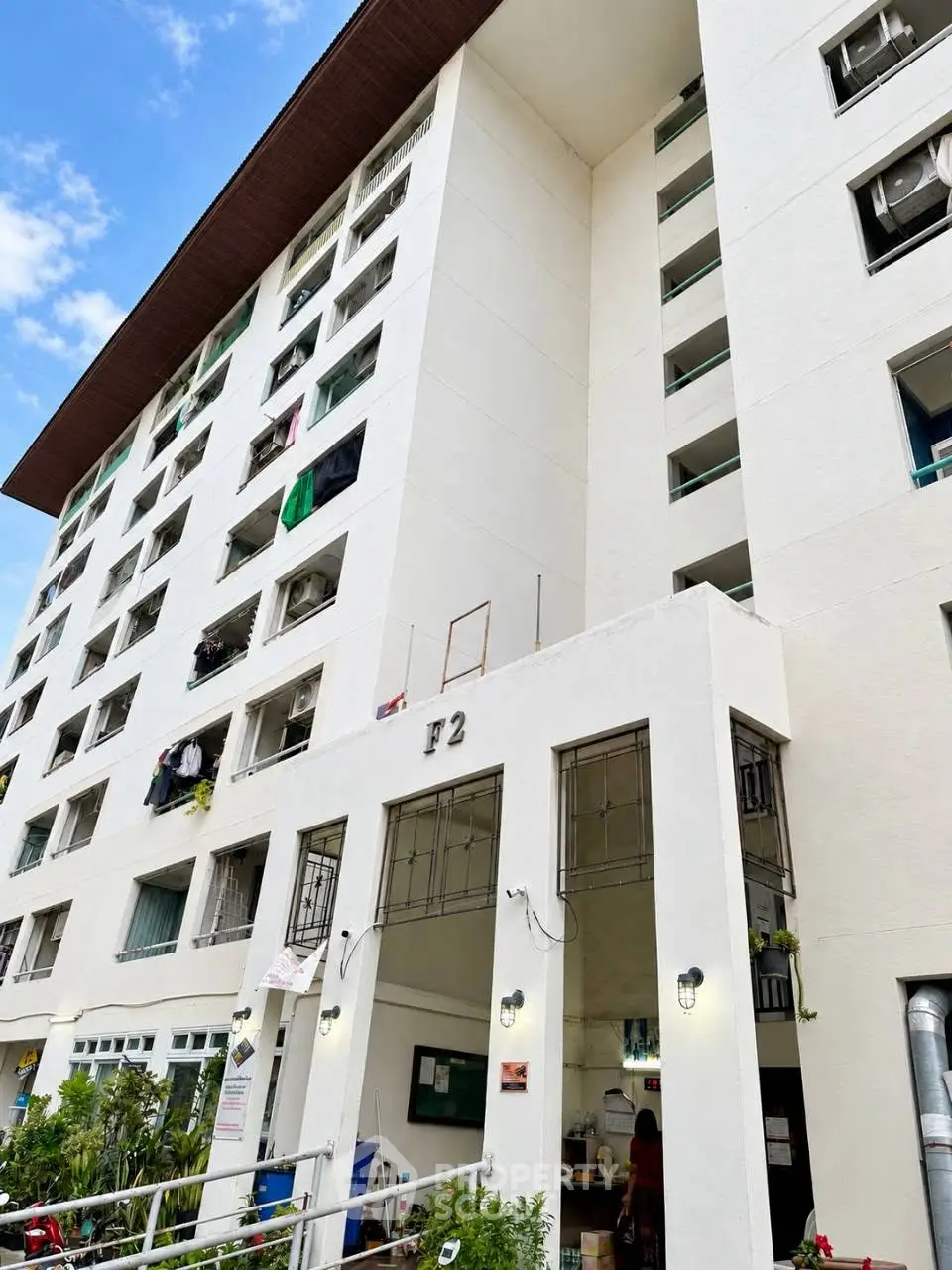 Modern multi-story residential building with balconies and entrance, showcasing urban living.