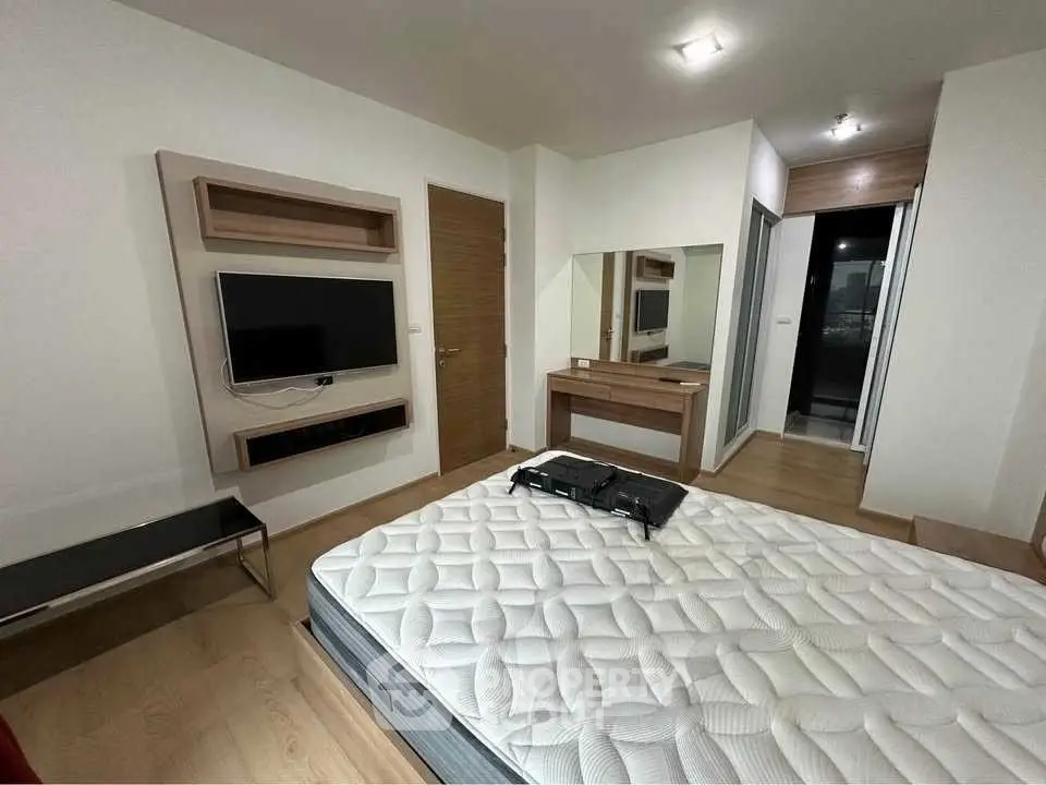 Modern bedroom with wall-mounted TV and stylish wooden furniture, perfect for comfortable living.