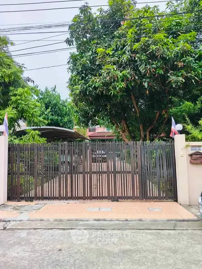 Charming residential entrance with wooden gate and lush greenery