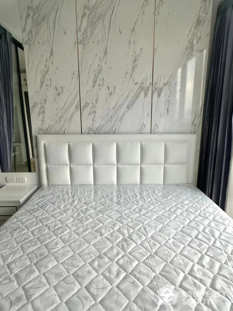 Luxurious bedroom with elegant marble accent wall and plush white headboard