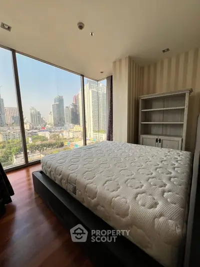 Spacious bedroom with large windows offering stunning city views.