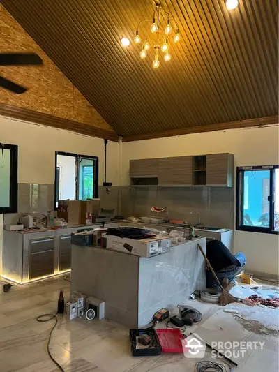 Modern kitchen under renovation with high ceiling and stylish lighting