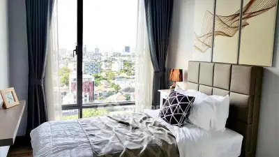 Modern bedroom with city view, featuring stylish decor and large windows for natural light.