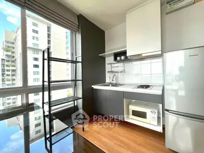 Modern kitchen with sleek design, large window view, and essential appliances in a high-rise apartment.