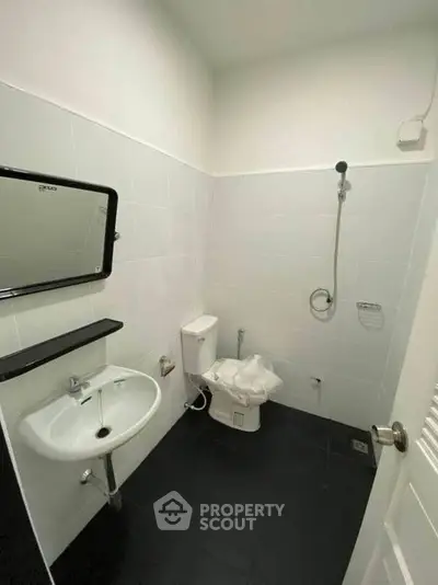 Modern minimalist bathroom with sleek fixtures and black tile flooring.