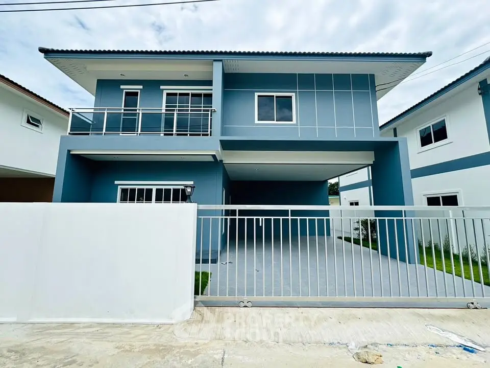 Modern two-story blue house with spacious driveway and sleek balcony.