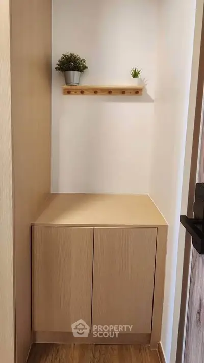 Stylish minimalist storage nook with wooden cabinet and decorative shelf.