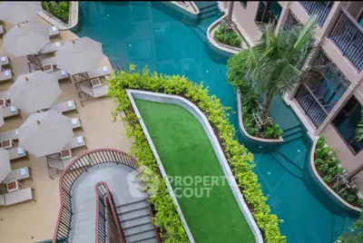Luxurious resort-style pool with lush greenery and sun loungers, perfect for relaxation.