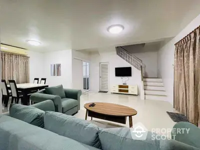 Spacious living room with modern furniture and open layout, featuring a staircase and dining area.