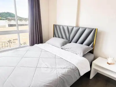 Modern bedroom with stylish headboard and large window offering natural light and scenic view.