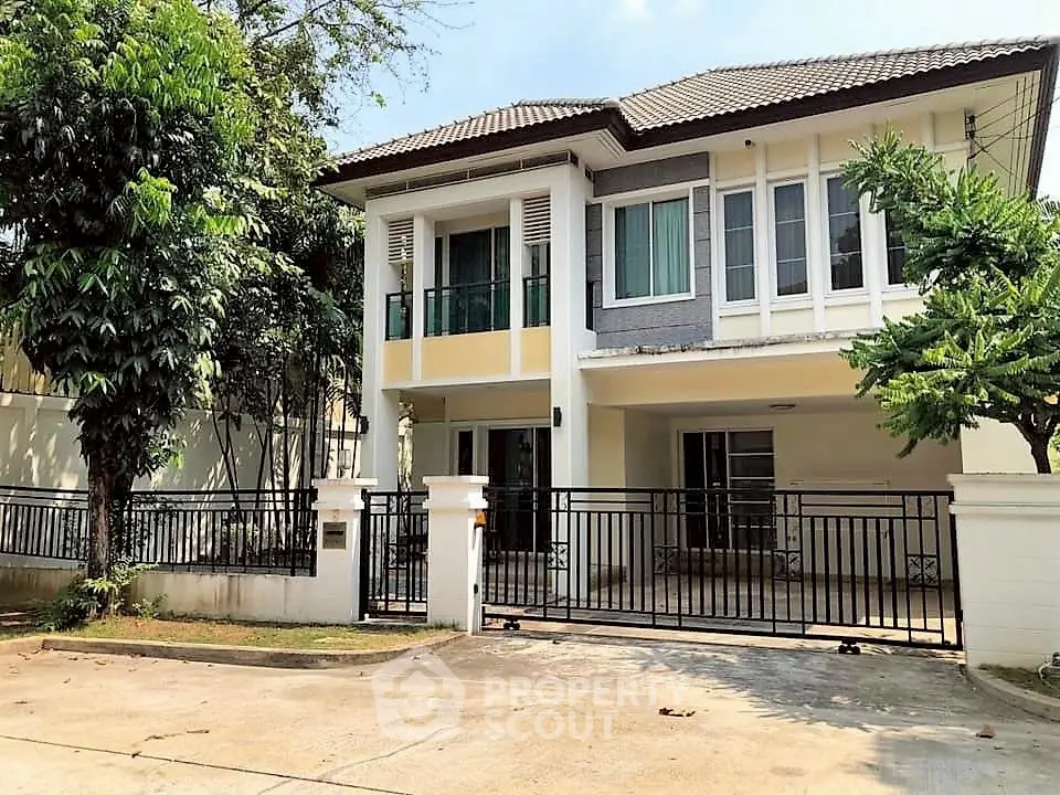 Charming two-story house with lush greenery and gated entrance