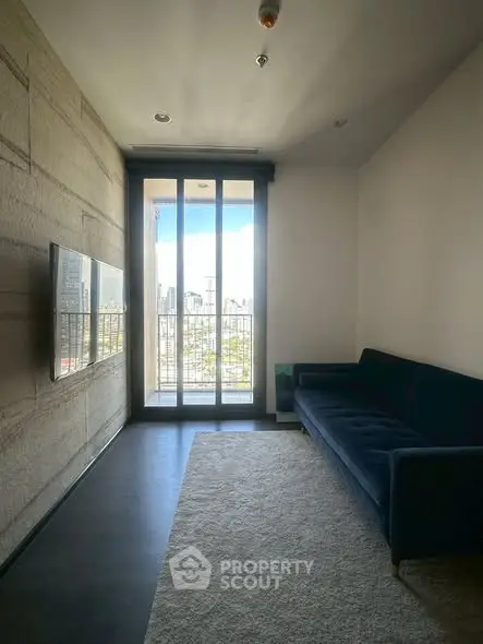Modern living room with large window and city view, featuring a sleek sofa and wall-mounted TV.