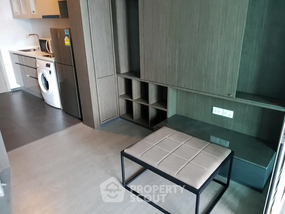 Modern apartment interior with sleek kitchen and laundry area, featuring stylish wooden cabinetry and contemporary furniture.