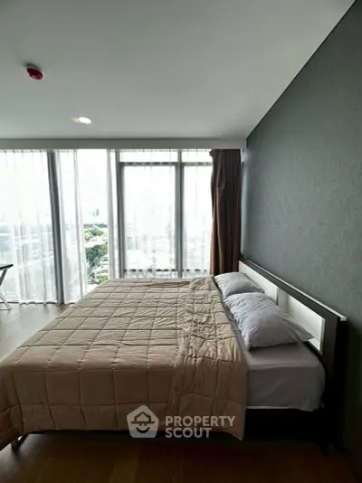 Spacious bedroom with large windows offering stunning city views in modern apartment.