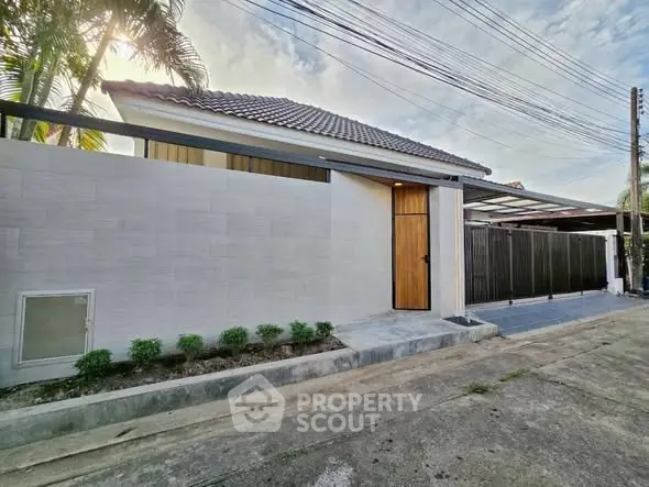 Modern single-story house with sleek exterior and tiled roof in a suburban setting.