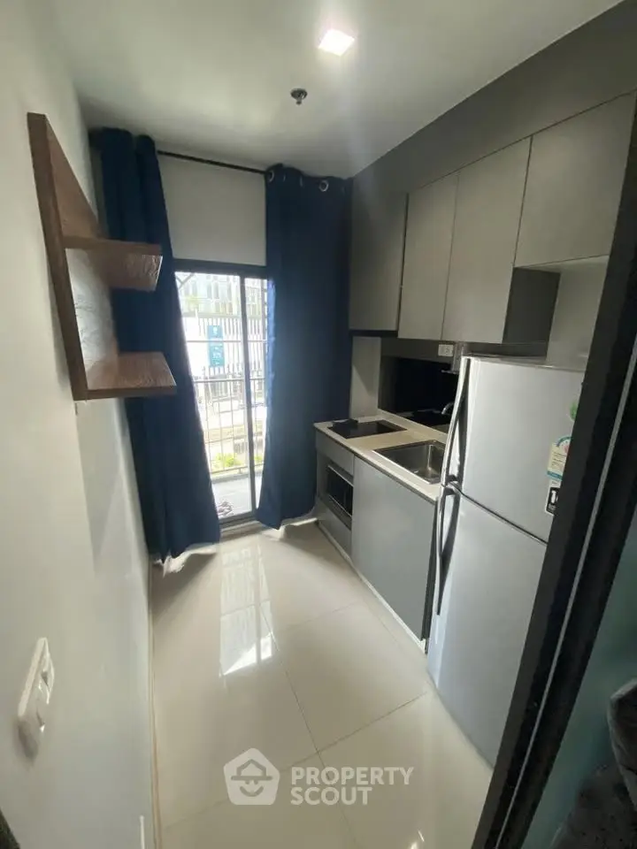 Modern compact kitchen with sleek cabinetry and stainless steel appliances in a stylish apartment.