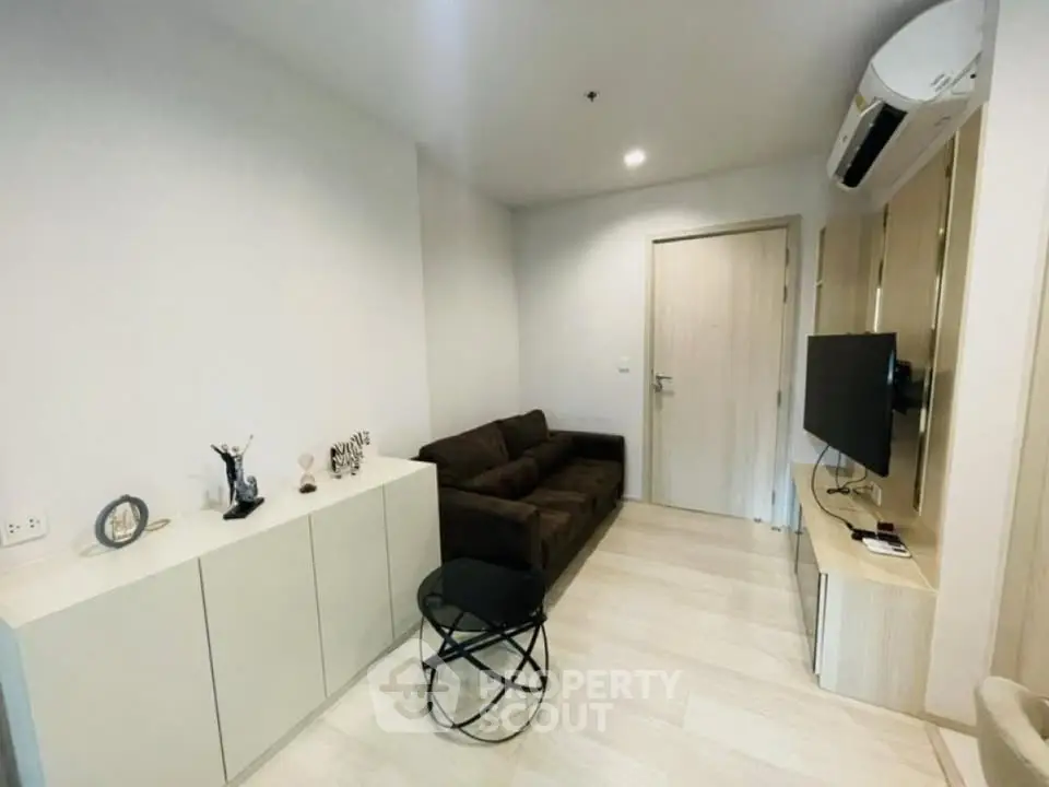 Modern living room with sleek furniture and wall-mounted TV in a cozy apartment.