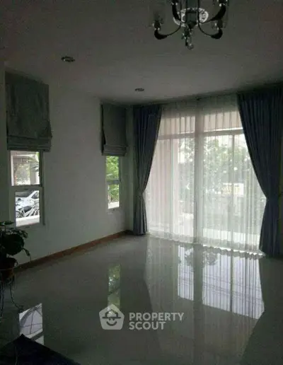 Spacious living room with large windows and elegant curtains, perfect for natural light.