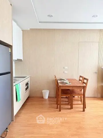 Modern kitchen with dining area featuring wooden furniture and sleek appliances.