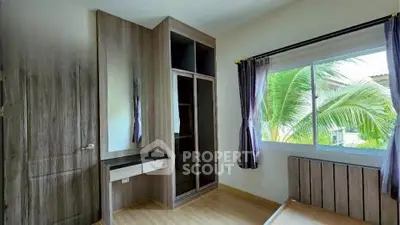 Spacious bedroom with built-in wardrobe and large window view
