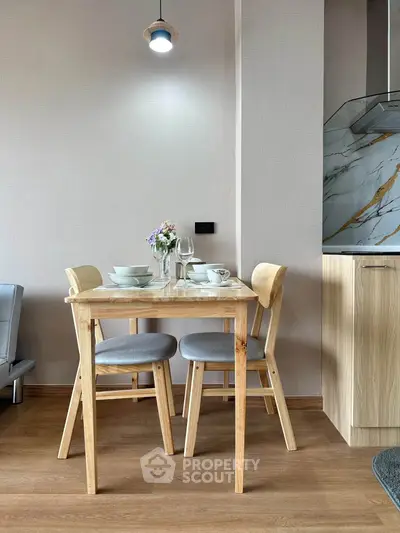 Charming dining area with wooden table and chairs, adjacent to a modern kitchen with marble accents.