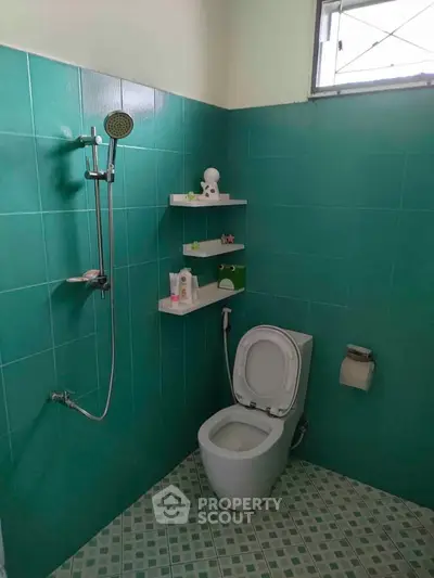 Modern bathroom with teal tiles and shower in a real estate property.