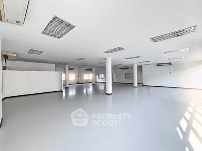 Spacious open-plan interior with modern lighting and large windows, ideal for versatile use.