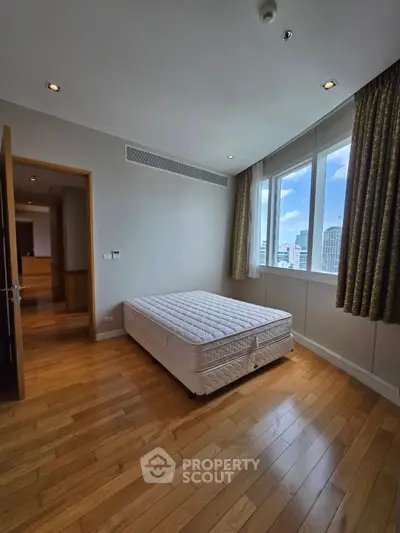 Spacious bedroom with large window and wooden flooring in modern apartment