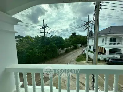 Charming balcony view overlooking a serene residential street with lush greenery.