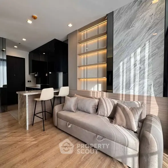 Modern living room with stylish decor and open kitchen layout, featuring elegant lighting and contemporary furniture.