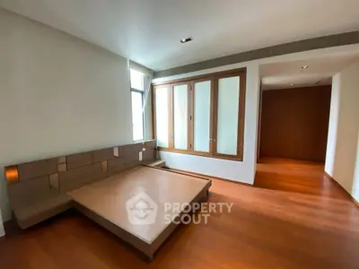 Spacious bedroom with wooden flooring and large windows in modern apartment