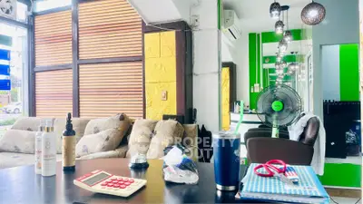 Modern living room with stylish decor and cozy seating area, featuring vibrant green accents and ample natural light.