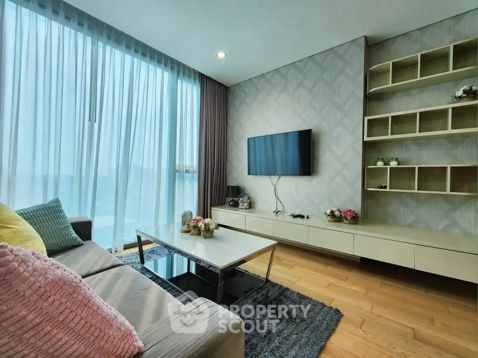 Modern living room with stylish decor, large window, and mounted TV, perfect for relaxation and entertainment.