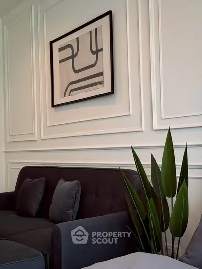 Stylish modern living room with elegant wall art and cozy dark sofa.