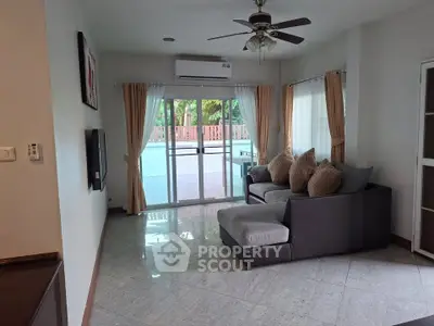 Spacious living room with modern sofa and large windows opening to a balcony.