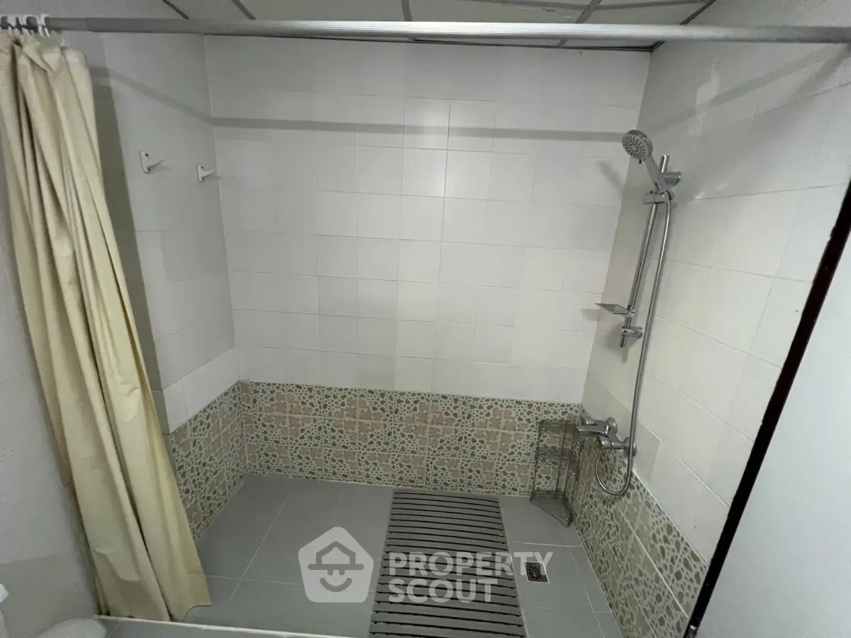 Spacious bathroom with tiled walls and modern shower fixtures, ideal for relaxation and comfort.