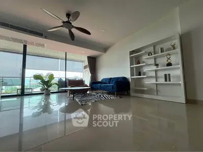 Spacious modern living room with large balcony and ocean view, featuring elegant decor and ample natural light.