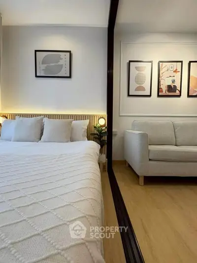 Modern bedroom with cozy bed and stylish decor, featuring a comfortable sofa and elegant wall art.