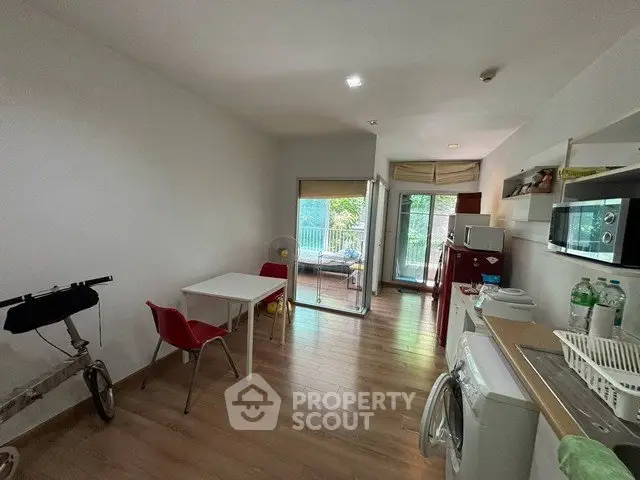 Modern open-layout kitchen with dining area and balcony access, featuring wooden flooring and contemporary appliances.