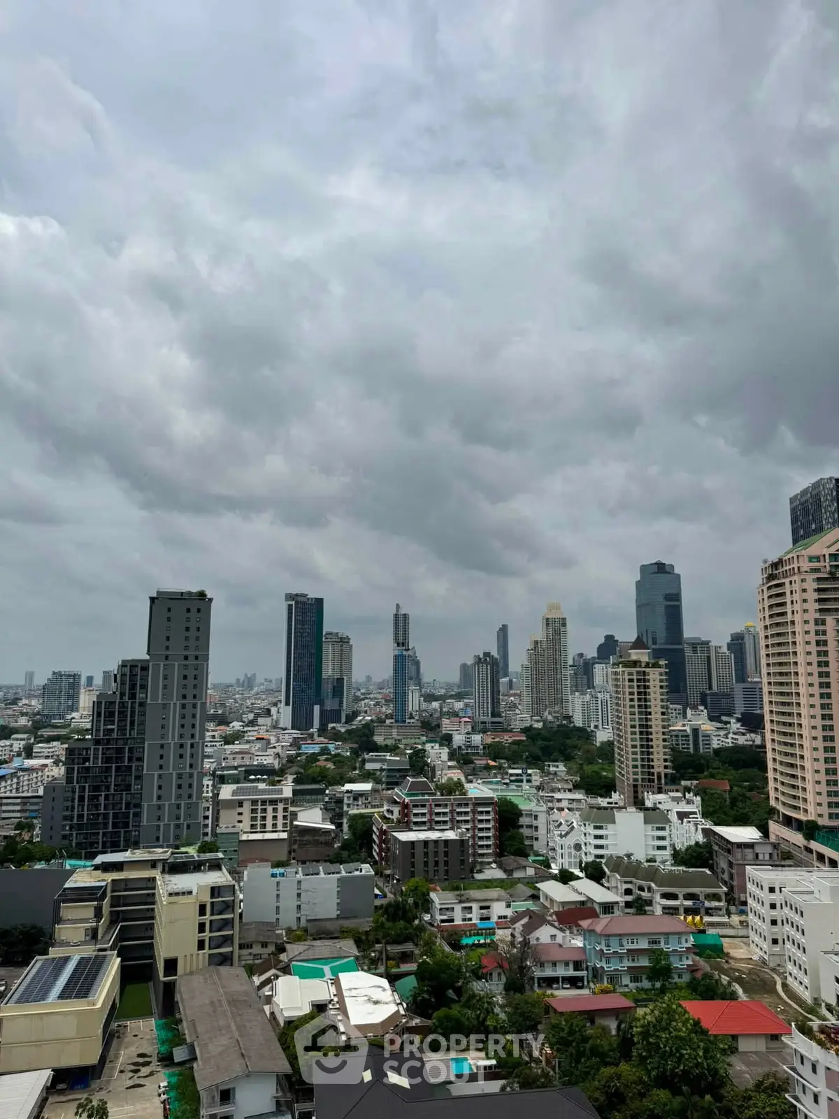 Stunning cityscape view from a high-rise building showcasing urban skyline and lush greenery.