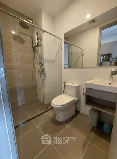 Modern bathroom with glass shower and sleek fixtures in contemporary apartment.