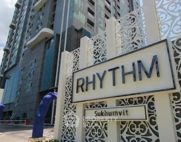 Modern high-rise building exterior with stylish facade and prominent Rhythm Sukhumvit signage.