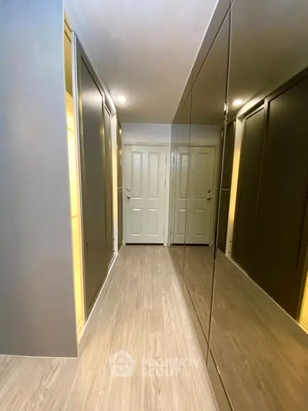 Modern hallway with sleek mirrored closets and wooden flooring