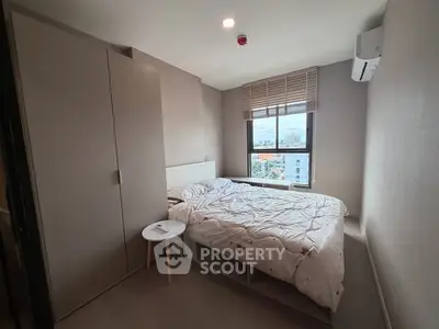 Modern bedroom with large window and minimalist decor in urban apartment.