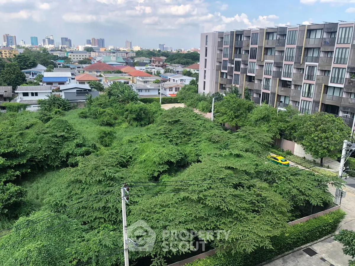 Stunning cityscape view from a modern apartment balcony overlooking lush greenery and urban skyline.