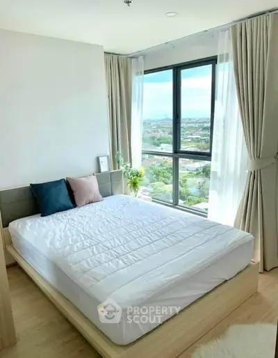 Bright and airy bedroom with large window offering stunning city views, modern decor, and cozy ambiance.