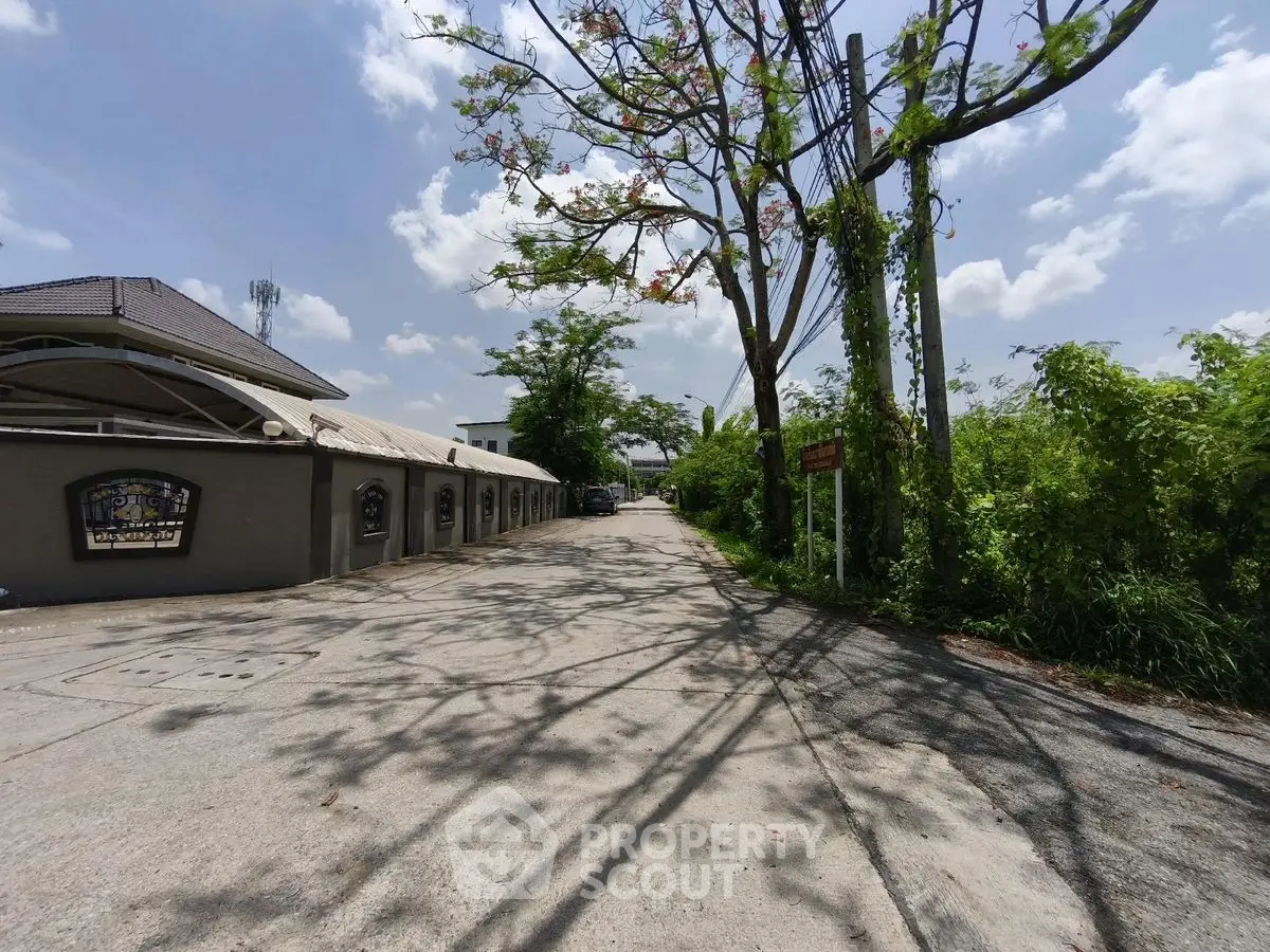Spacious driveway with lush greenery and clear blue sky in a serene neighborhood.