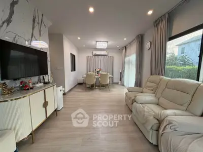 Spacious living room with modern decor and dining area, featuring elegant furniture and natural light.