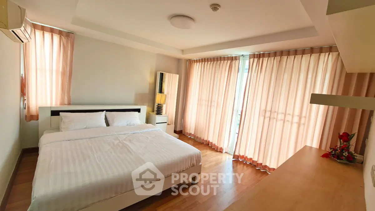 Spacious bedroom with large windows and elegant curtains, perfect for natural light lovers.