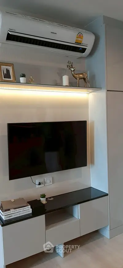 Modern living room with sleek TV setup and air conditioning unit.